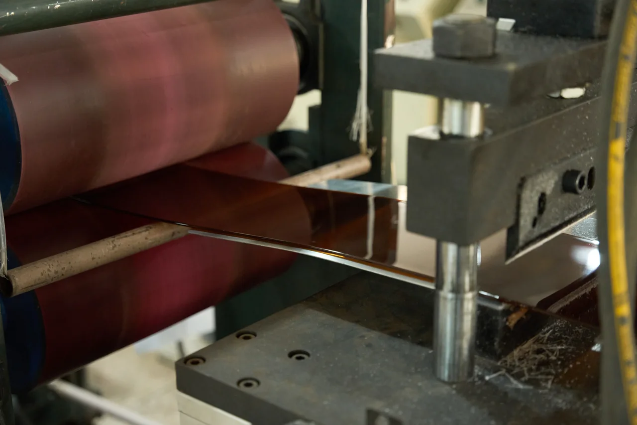 An acetate sheet passing through rollers.