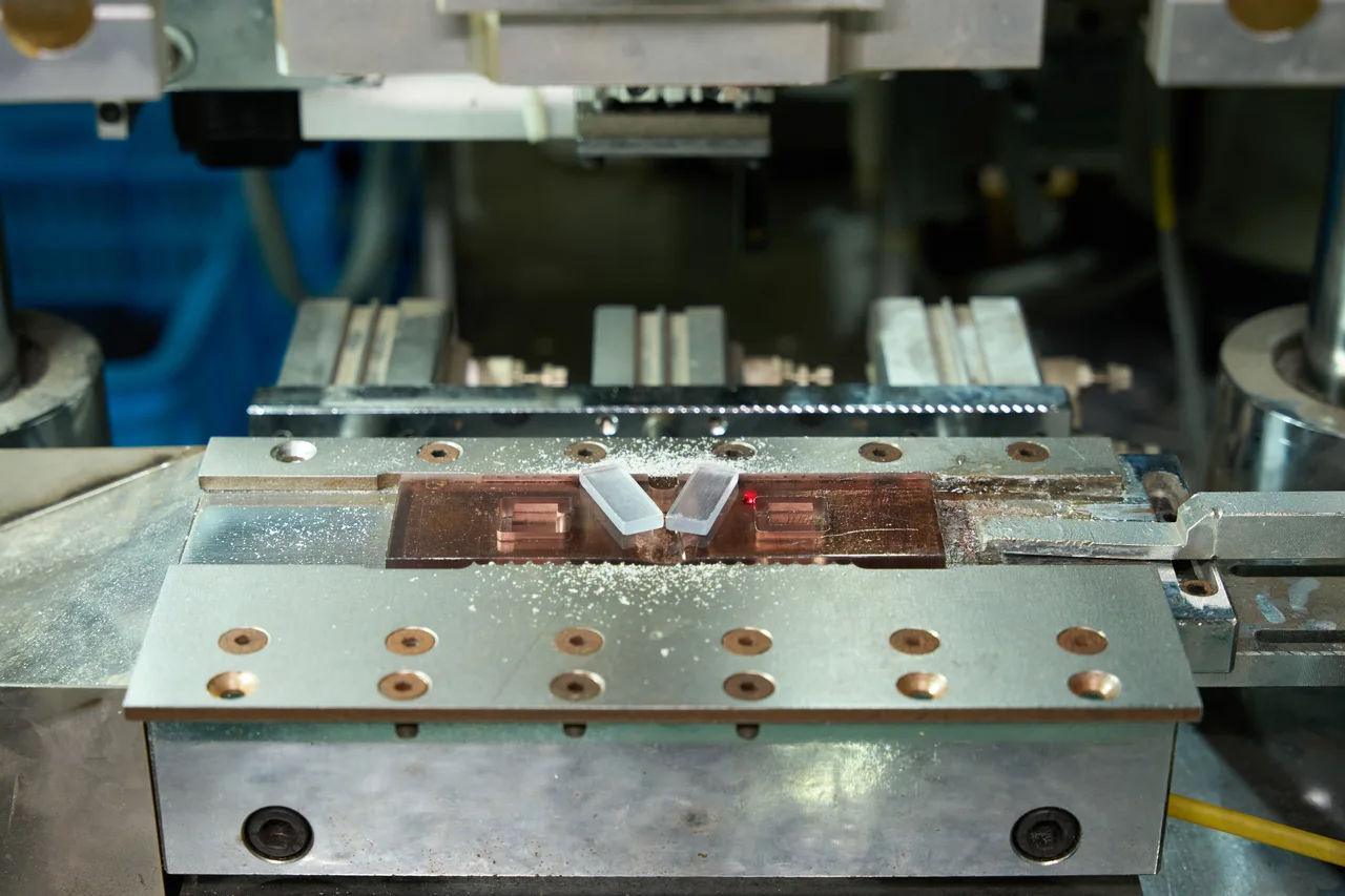 Small acetate components held in a machining fixture.