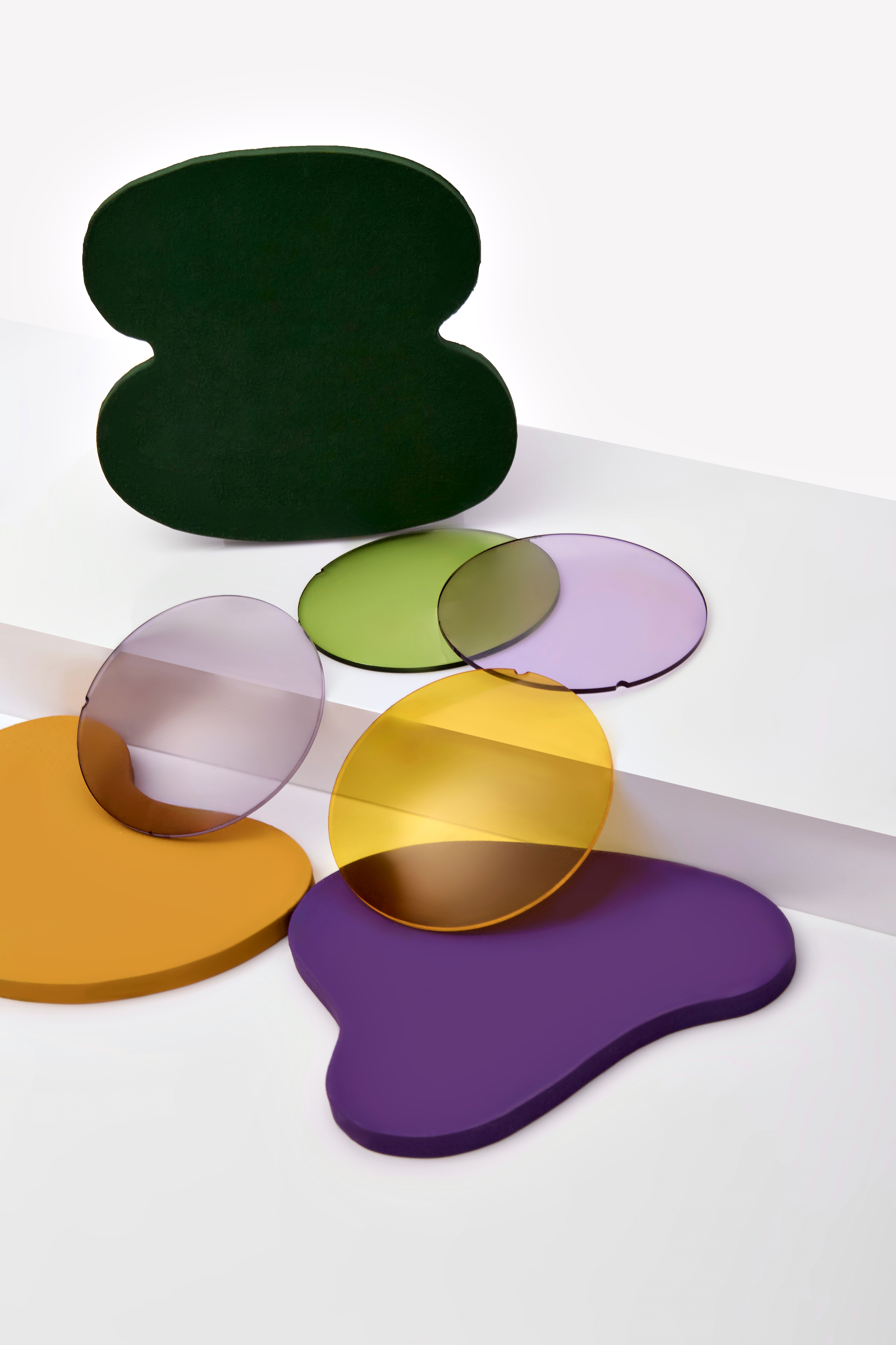 Circular sun-lens samples in different colours on green, violet and yellow geometric shapes