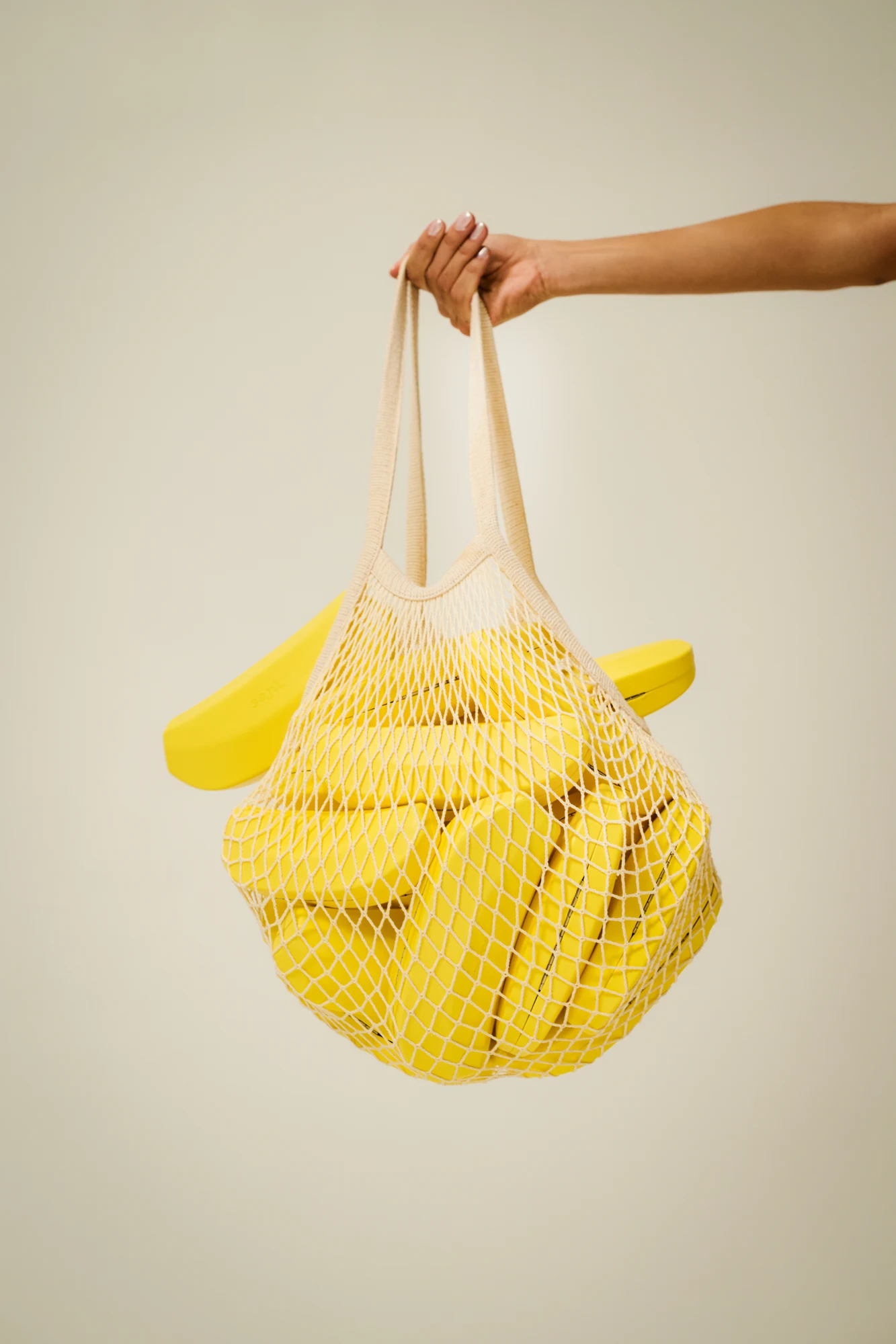 Mano che regge una borsa gialla intrecciata piena di Banana Case