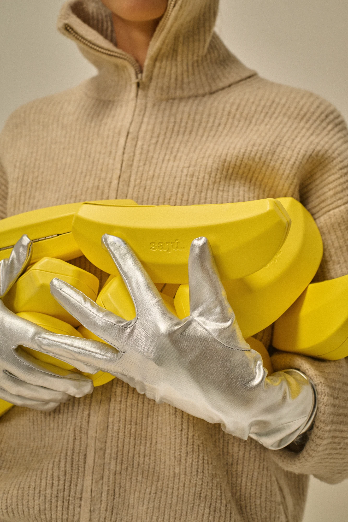 Mani con guanti argentati che sorreggono diversi Banana Case gialli