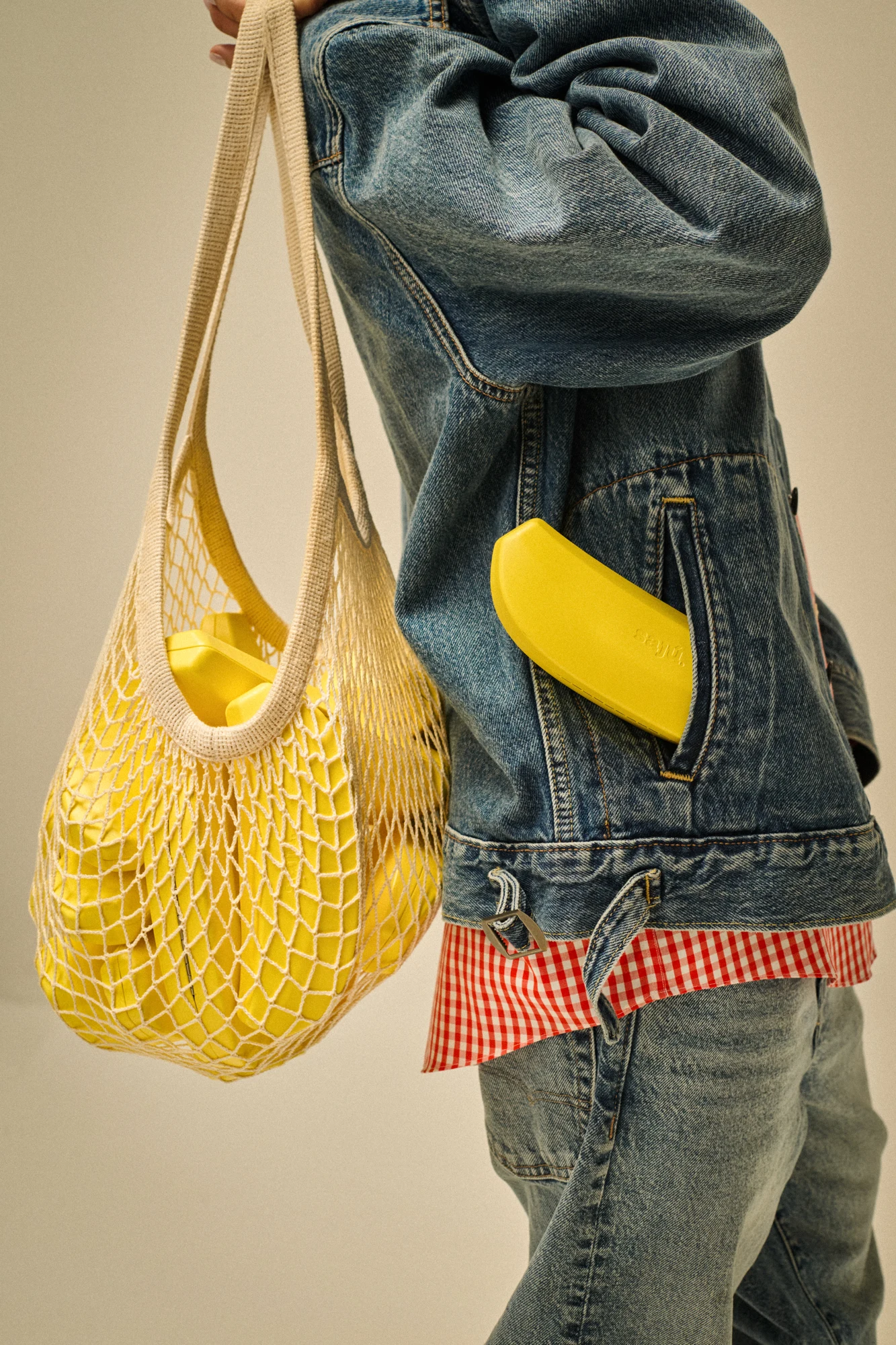 Banana Case giallo in una tasca di jeans accanto a una borsa gialla