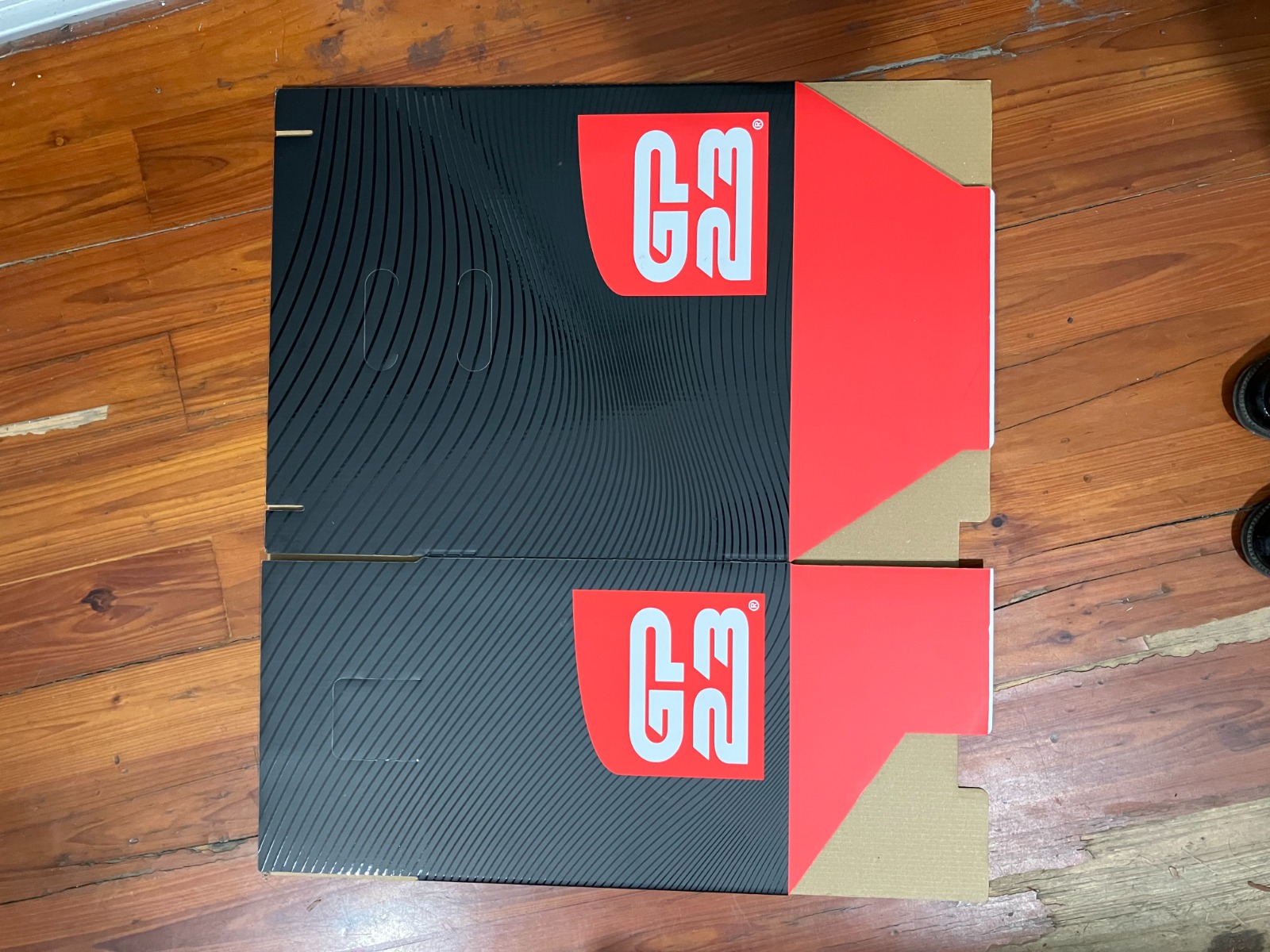Unfolded printed GP23 carton with glossy flowing lines on matte black and red flaps