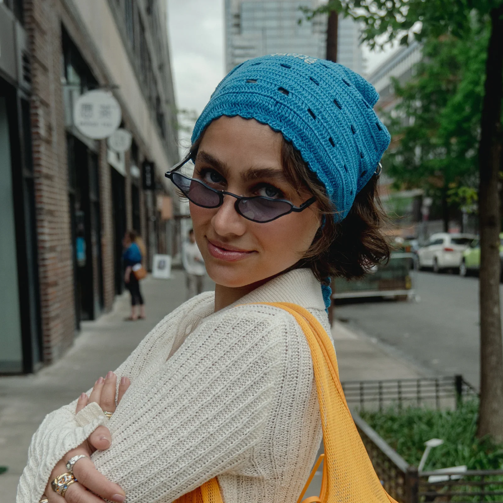 The organic sunglasses worn with a blue knit hat in daylight campaign photography