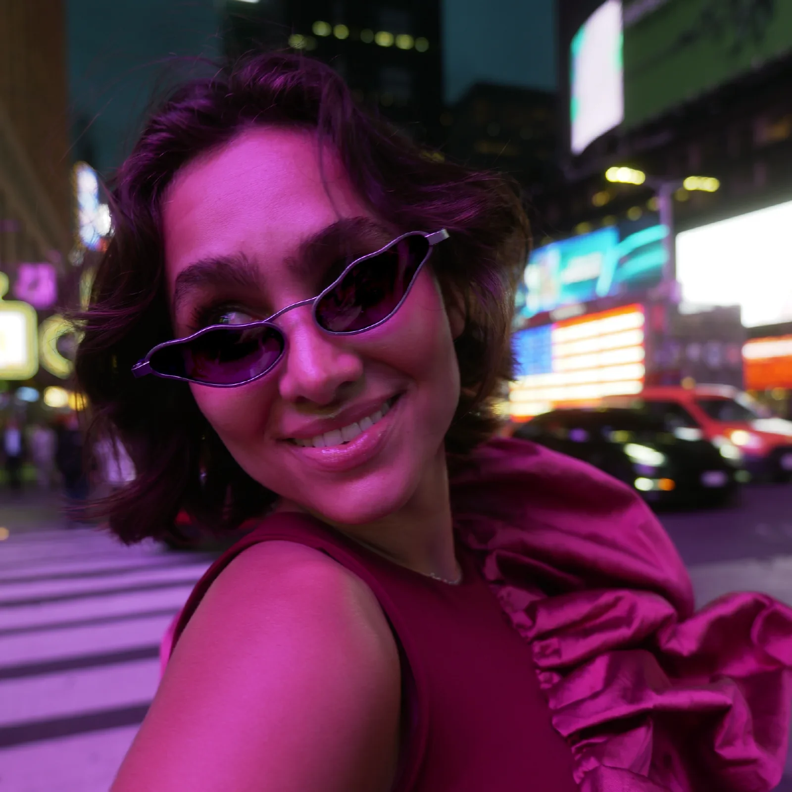 The organic sunglasses worn in a campaign portrait against colourful city lights