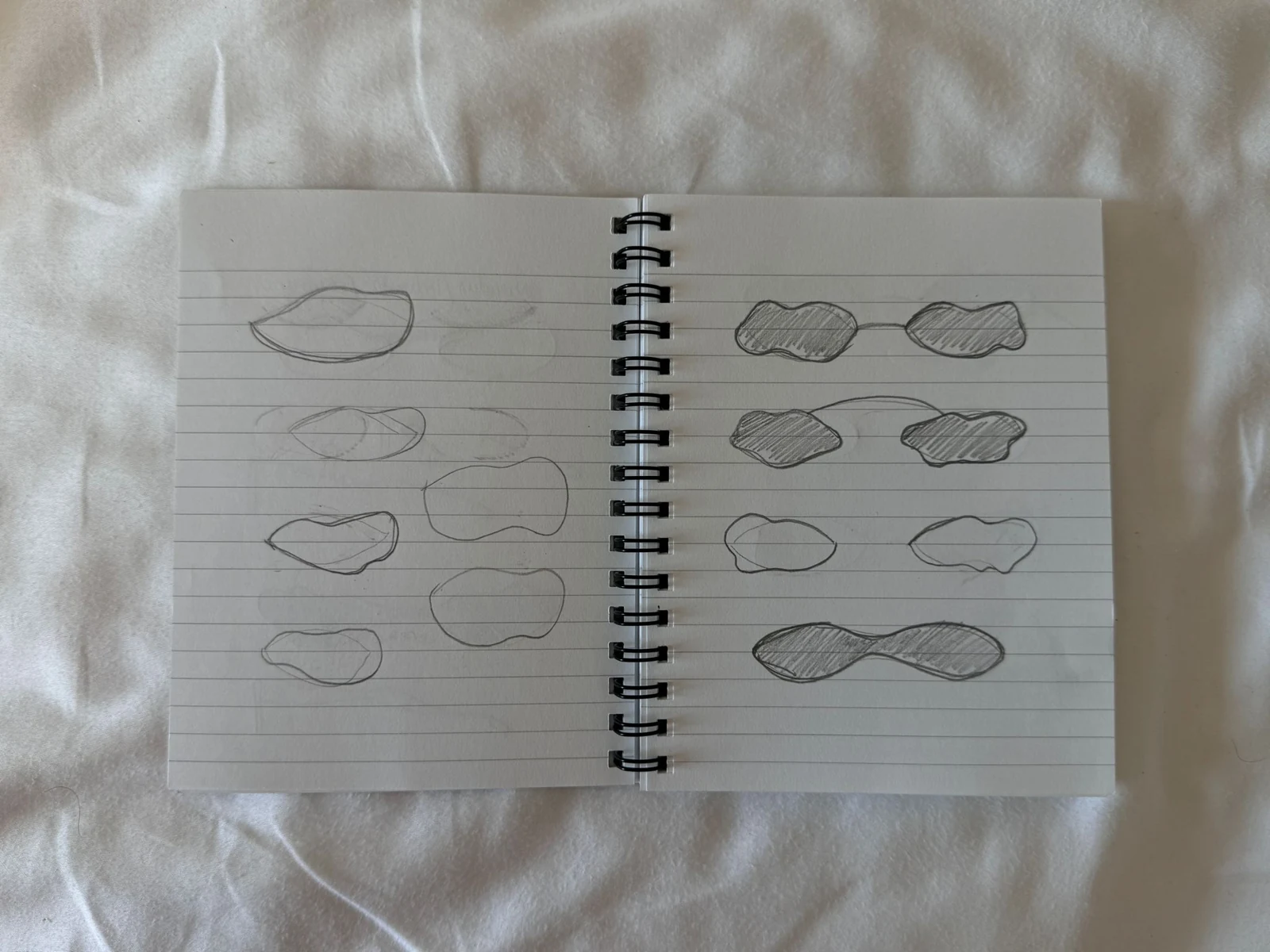 A second notebook spread exploring different organic eyewear outlines in pencil